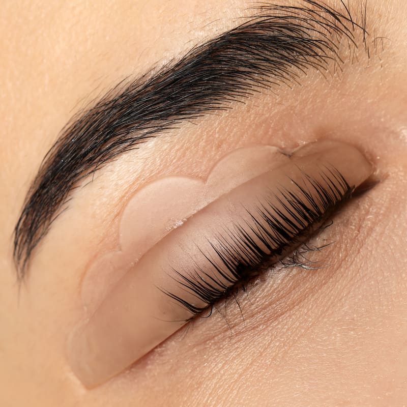 Young woman undergoing eyelash lamination, closeup. Professional service